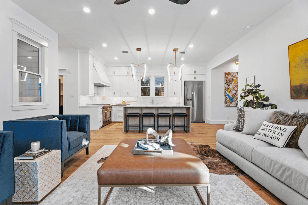 HDR real estate photograph of a light-filled living room and kitchen with natural window views.