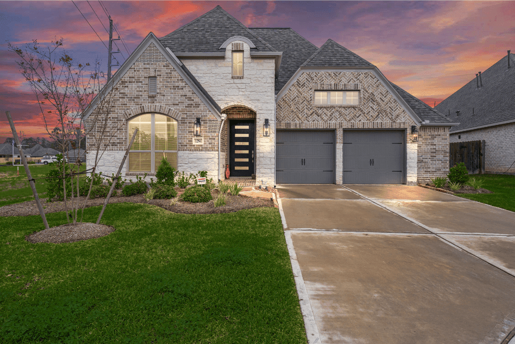 Twilight property photograph showing warm windows, exterior lights, and an evening sky.
