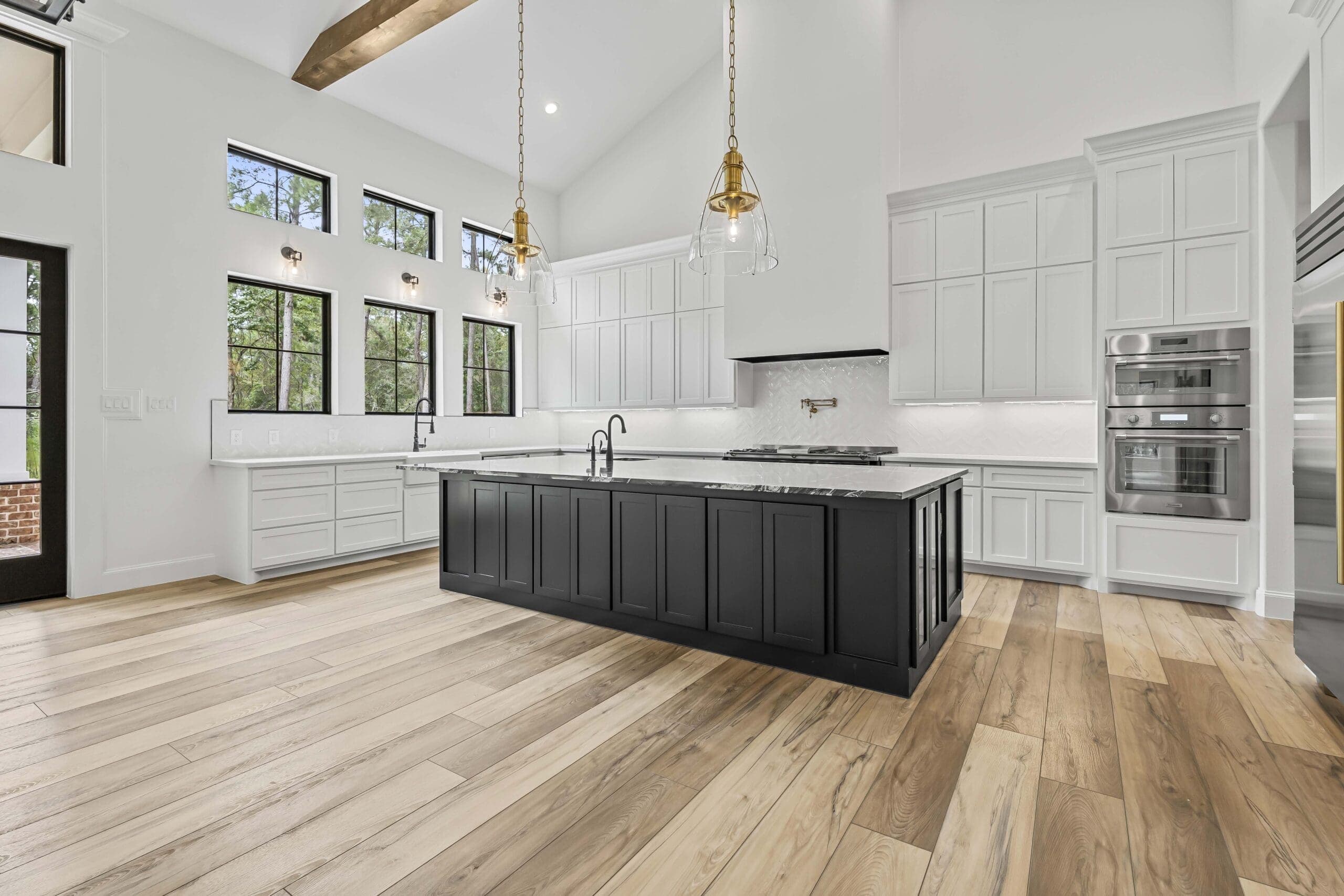 Professional real estate photography of a bright luxury kitchen with a black island in the Greater Houston area
